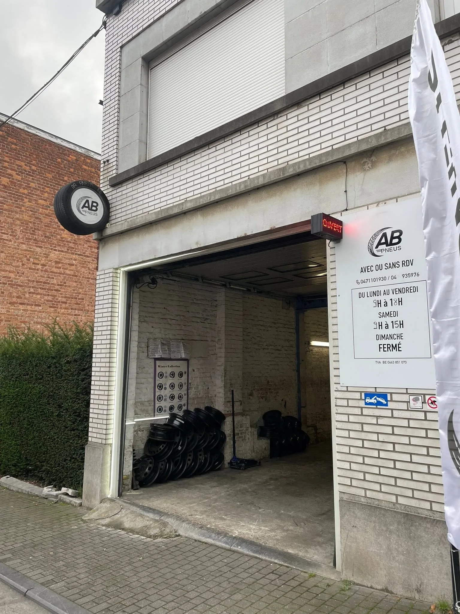 Entrée du garage AB Pneus, Rue St Laurent 205 à Liège, avec enseigne et jantes visibles dans l'atelier